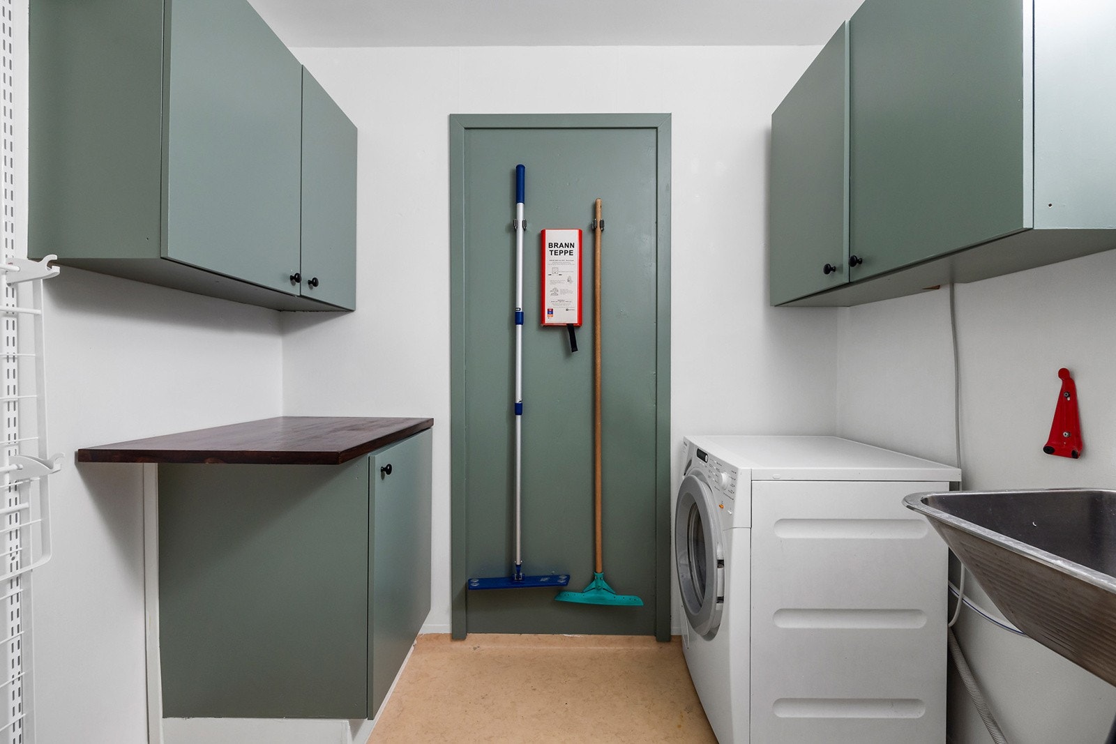 Praktisk vaskerom med veggskap, utslagskum og opplegg for vaskemaskin. Galleribilde