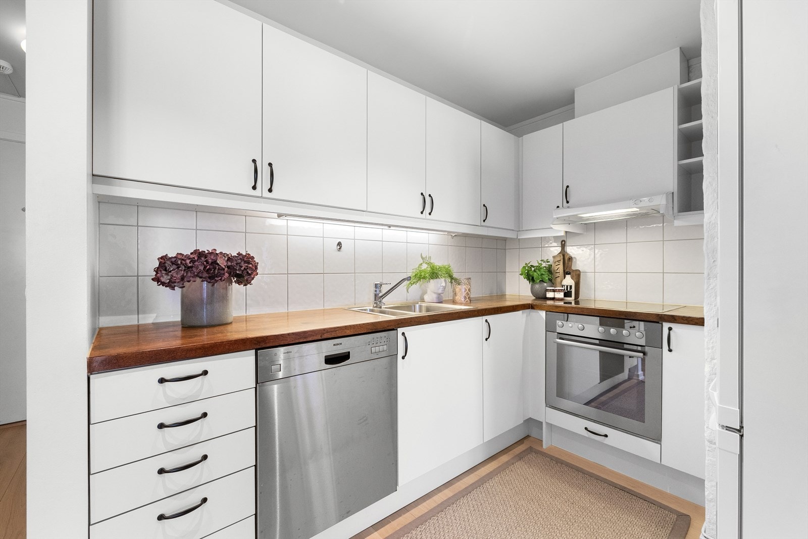 Moderne kjøkken med slette fronter og heltre benkeplate med integrert oppvaskkum og ettgreps blandebatteri. Galleribilde