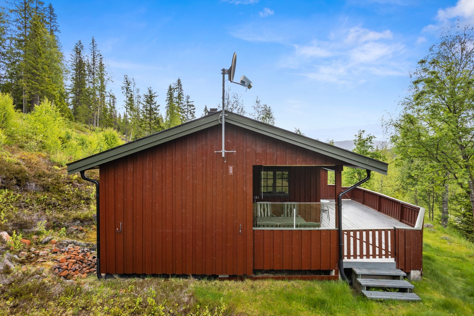 Tretrapp leder ned til terreng via port og videre opp til uthuset Galleribilde