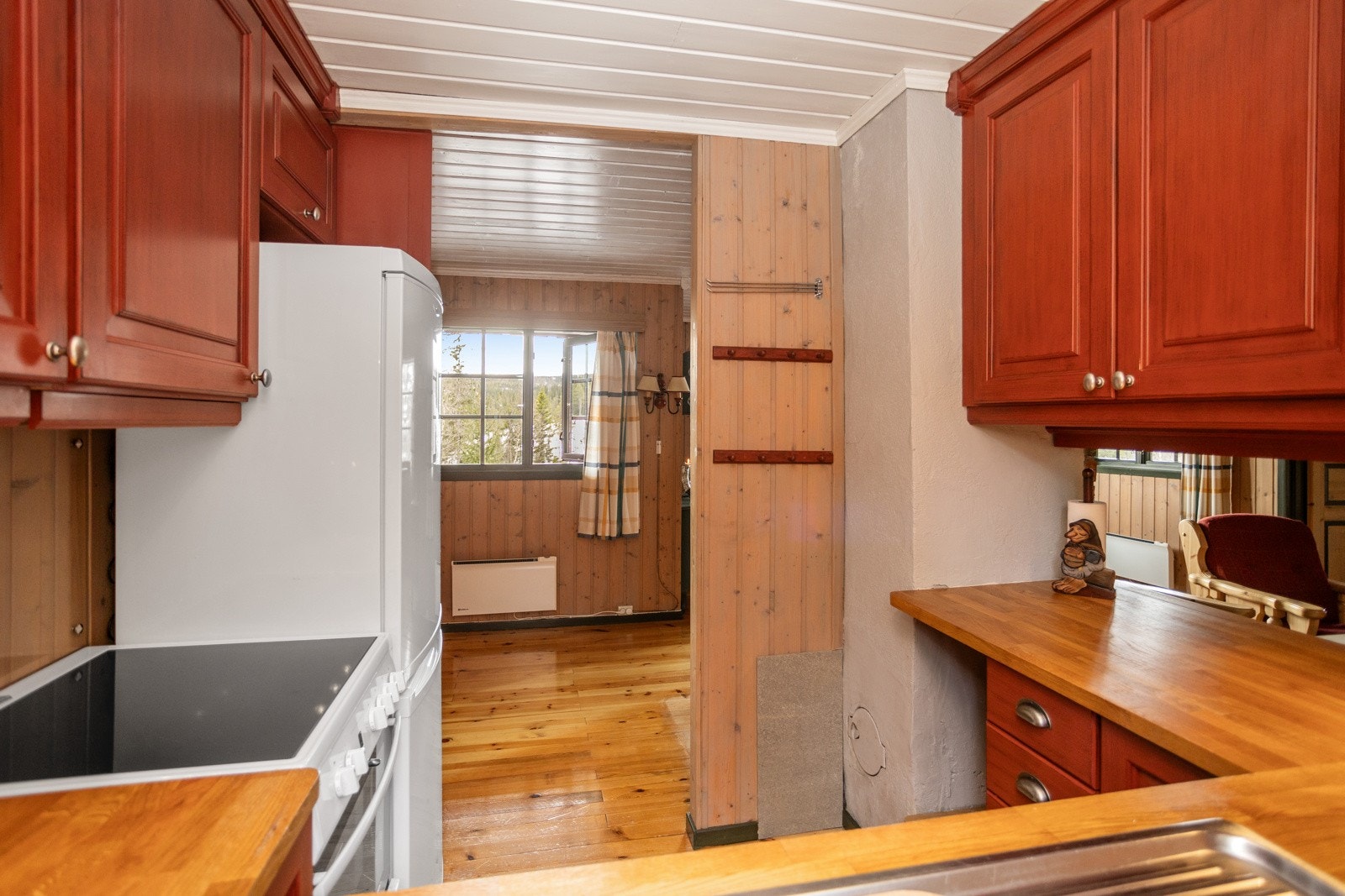 Frittstående komfyr og kjøleskap. Ventilator med riekte avtrekk montert over komfyren Galleribilde