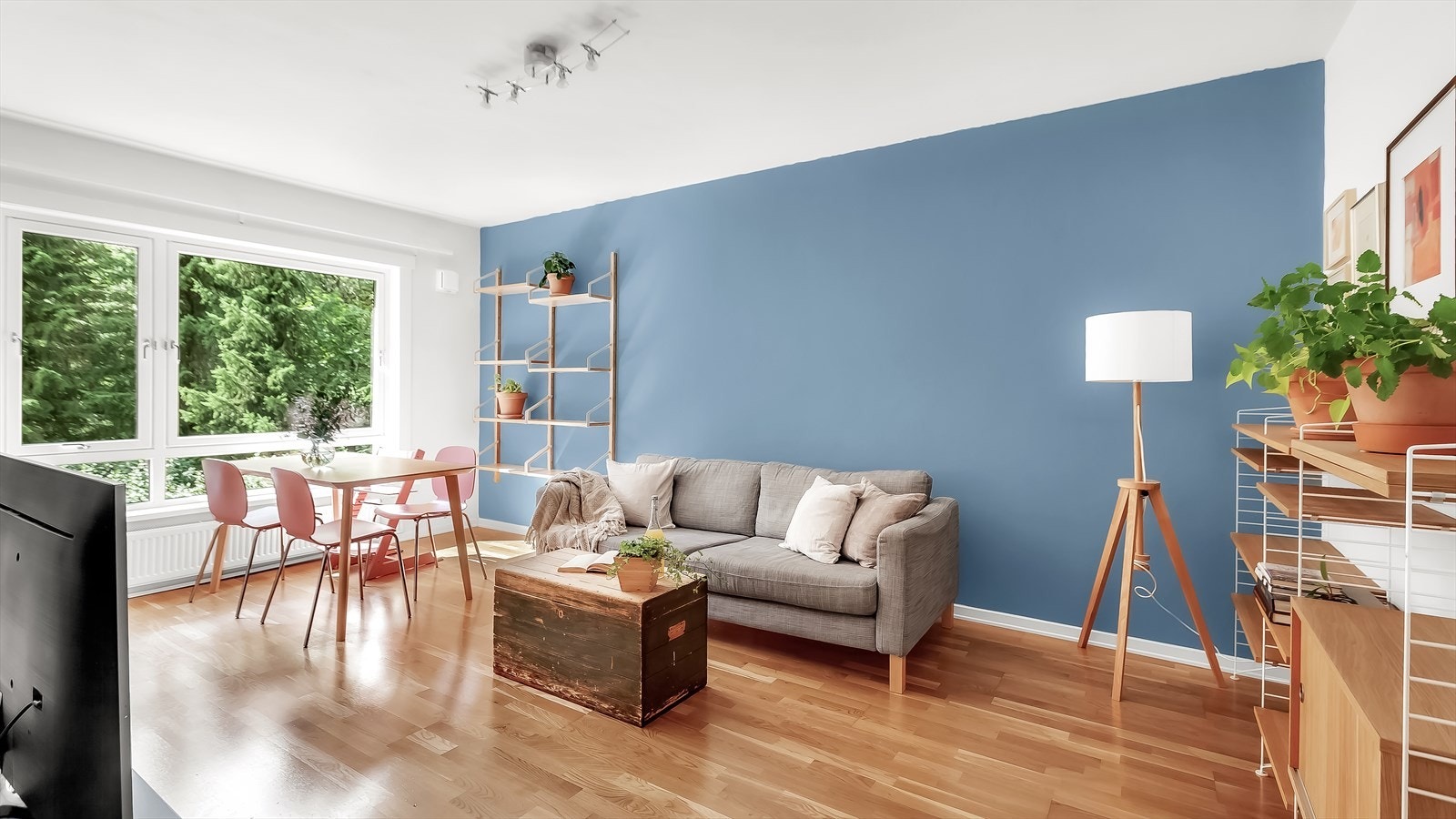 Stuen har plass til både sofakrok og spisebord med tilhørende spisestuestoler. Leiligheten har gjennomgående planløsning og store vindusflater som gjør at rommene føles lyse og luftige Galleribilde