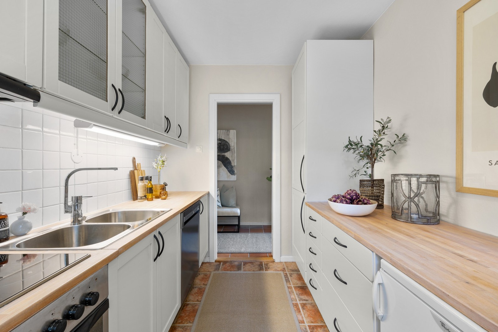 Kjøkkenet har en praktisk og klassisk layout med god utnyttelse av plassen. Innredningen består av funksjonelle skap- og hylleløsninger som gir rikelig med oppbevaringsmuligheter. Galleribilde