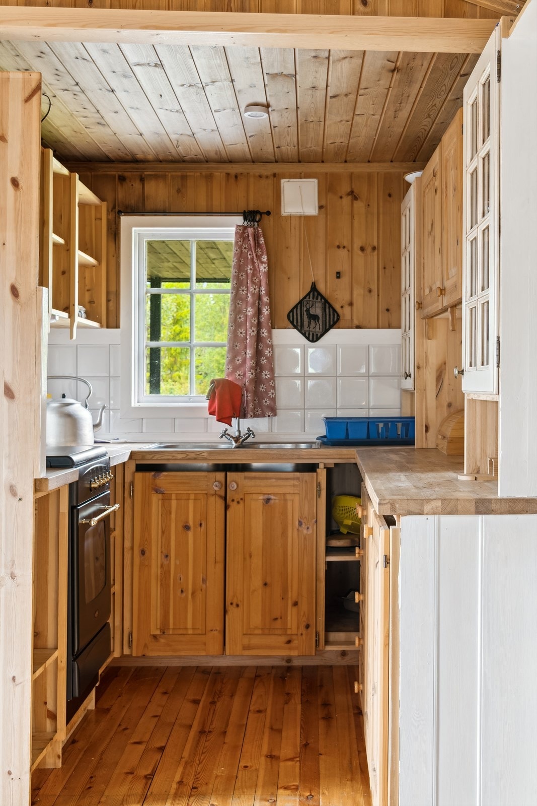 Kjøkkenet er utstyrt med en propankomfyr, og det er fliser over benken. Avløp for vaskevann går ut til terrenget. Det er kun veggventil for ventilasjon. Galleribilde