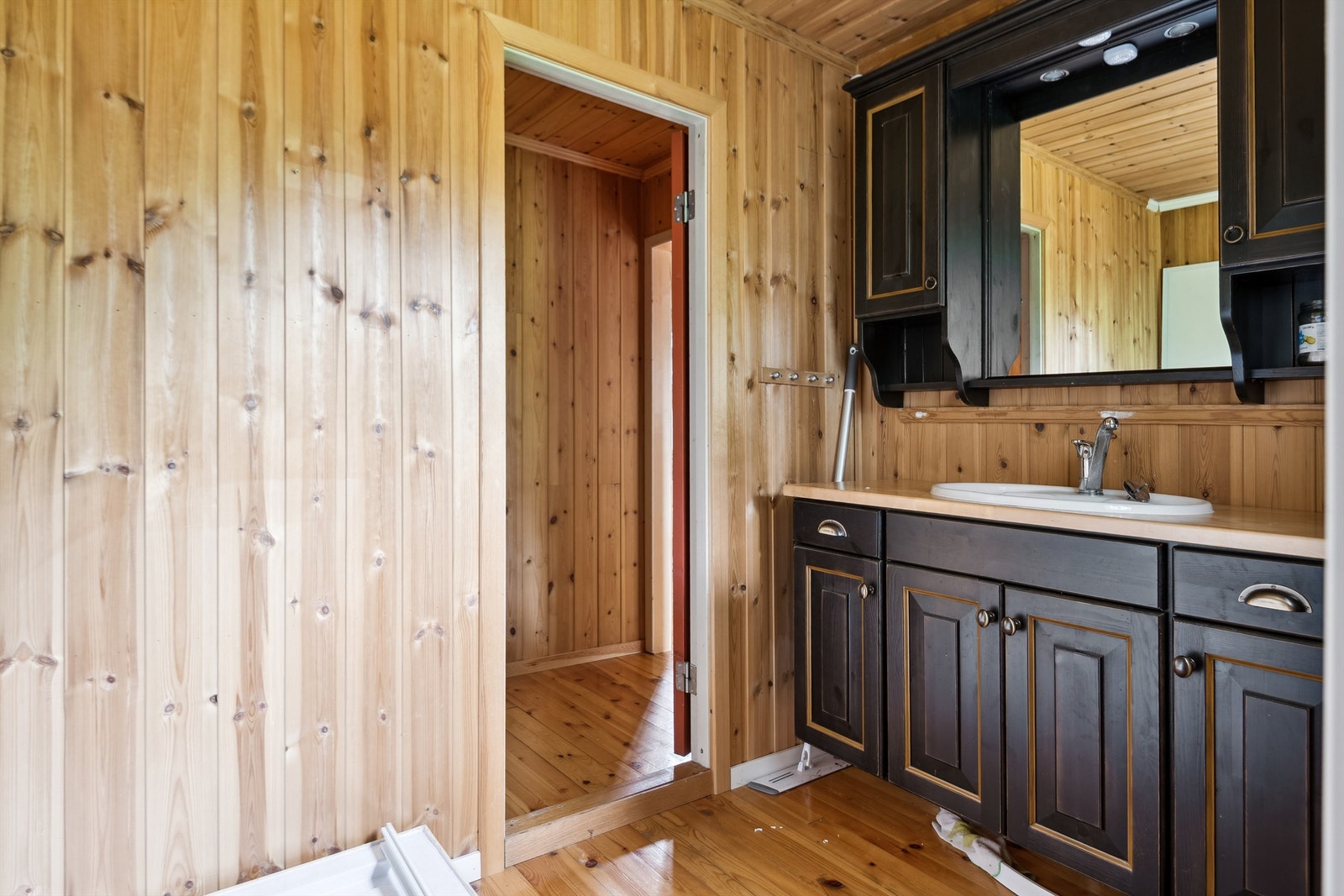 Et praktisk vaske- og stellerom fra 2008 med lakkert tregolv og panel på vegger og i tak. Rommet er innredet med et servantskap i heltre med nedfelt servant, overskap og speil med lys. Vann pumpes inn fra en tank, og det er avløp for gråvann. Galleribilde