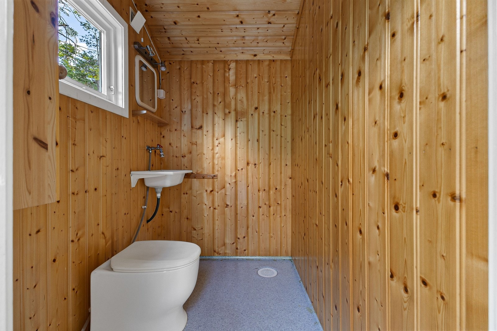 Det er utvendig adkomst til toalettrom. Toalettrommet har panel på vegger og himling og vinylbelegg op gulv. Den er utsyrt med snurredo og håndvask i pvc. Galleribilde