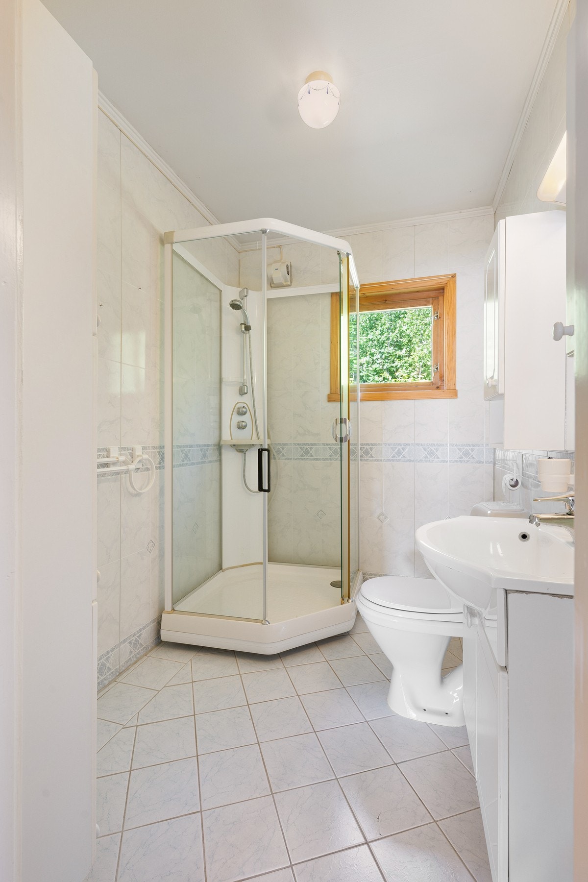 Badet inneholder servantinnredning, toalett og dusjkabinett Galleribilde