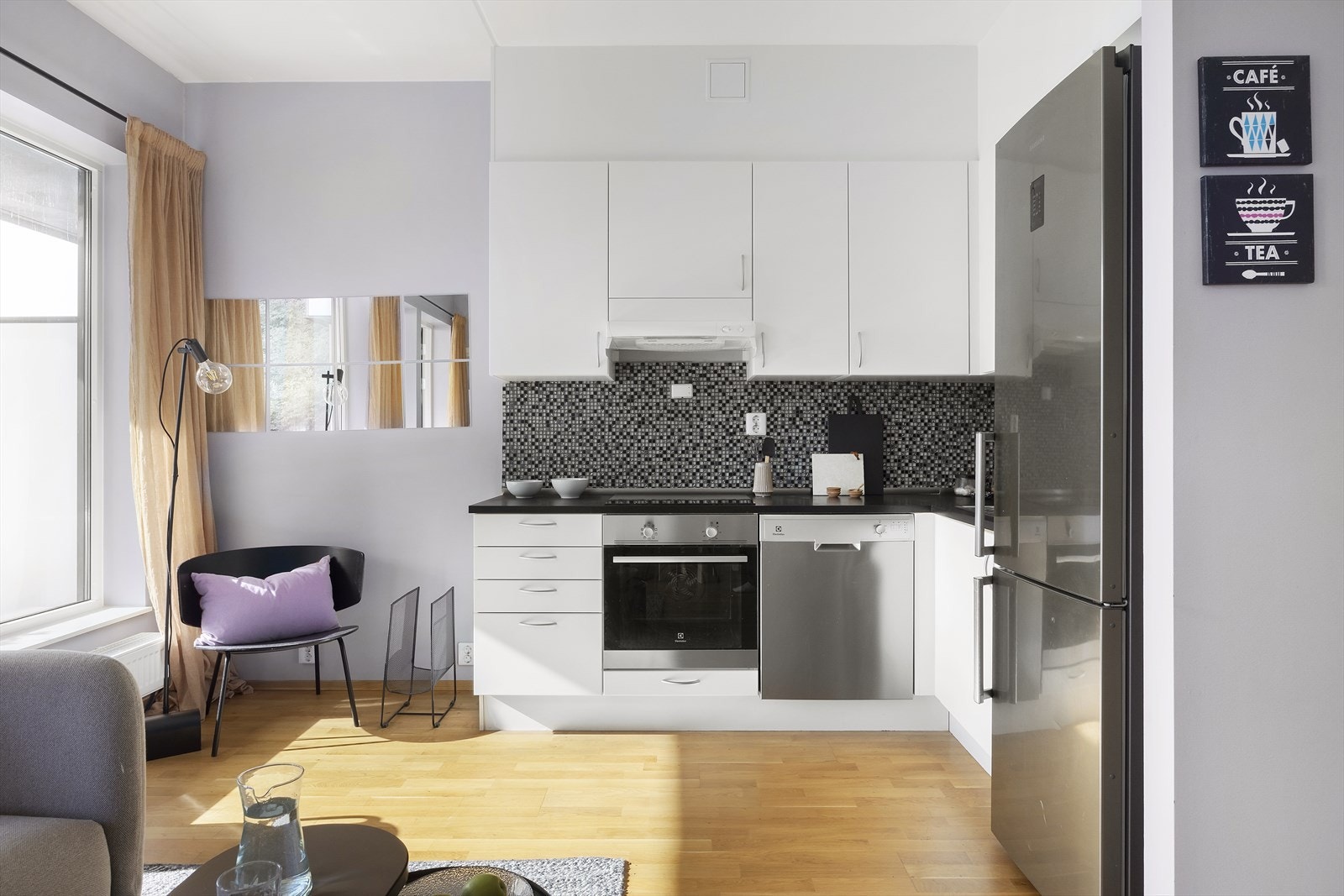 Kjøkkenet er utstyrt med integrerte hvitevarer som komfyr, platetopp og oppvaskmaskin, samt et frittstående kjøleskap Galleribilde