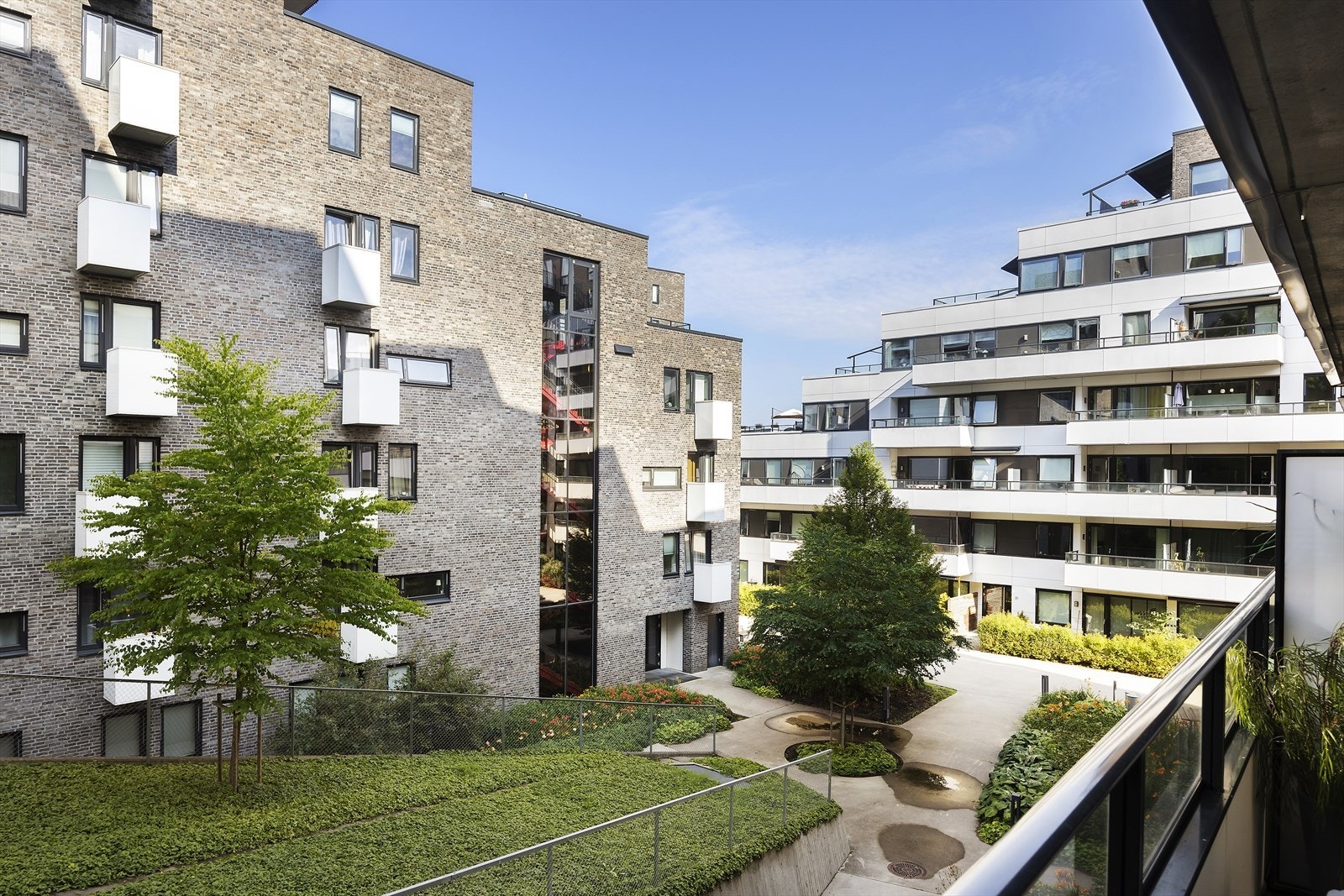 Utsikt fra balkongen mot grønne fellesarealer og nabobygg vendt mot soverom med minimalt innsyn Galleribilde