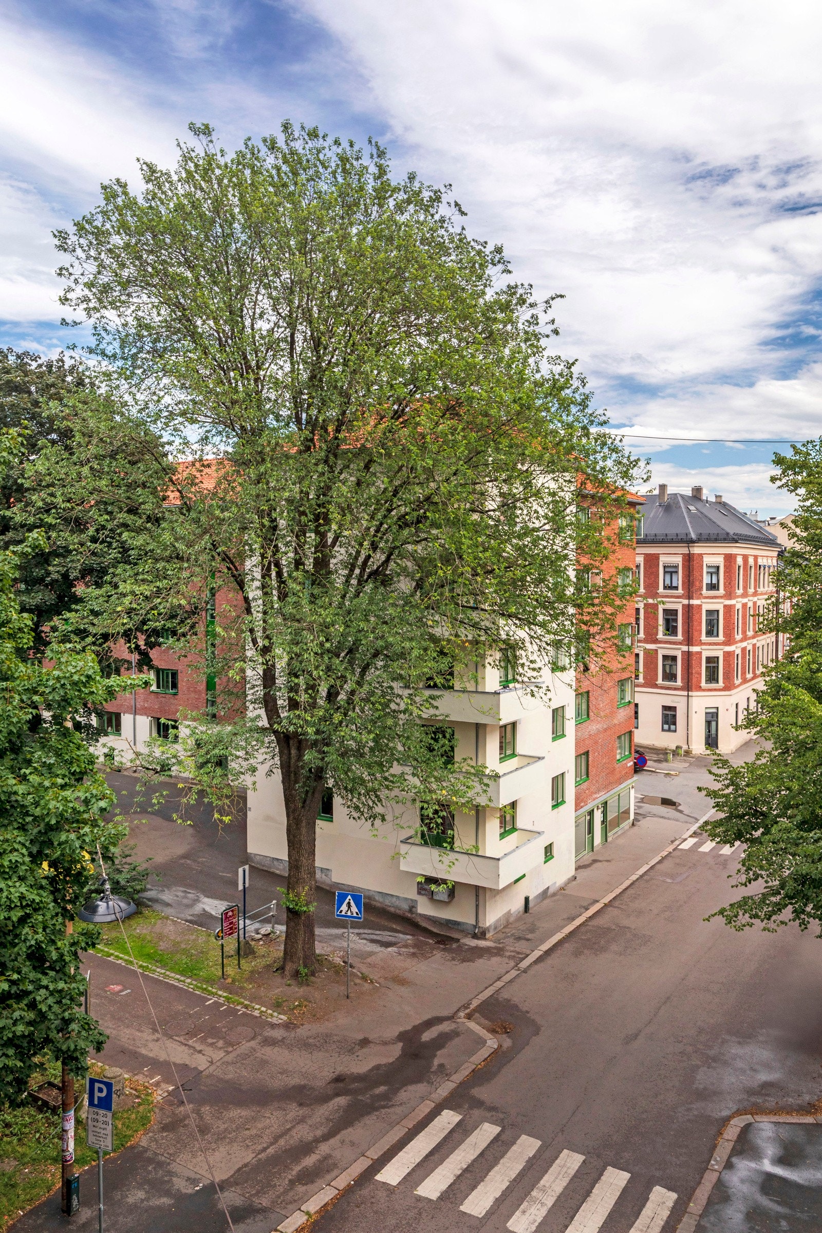 Leiligheten ligger høyt til i byggets 4 etg. og har grønne trær på hver side. Galleribilde