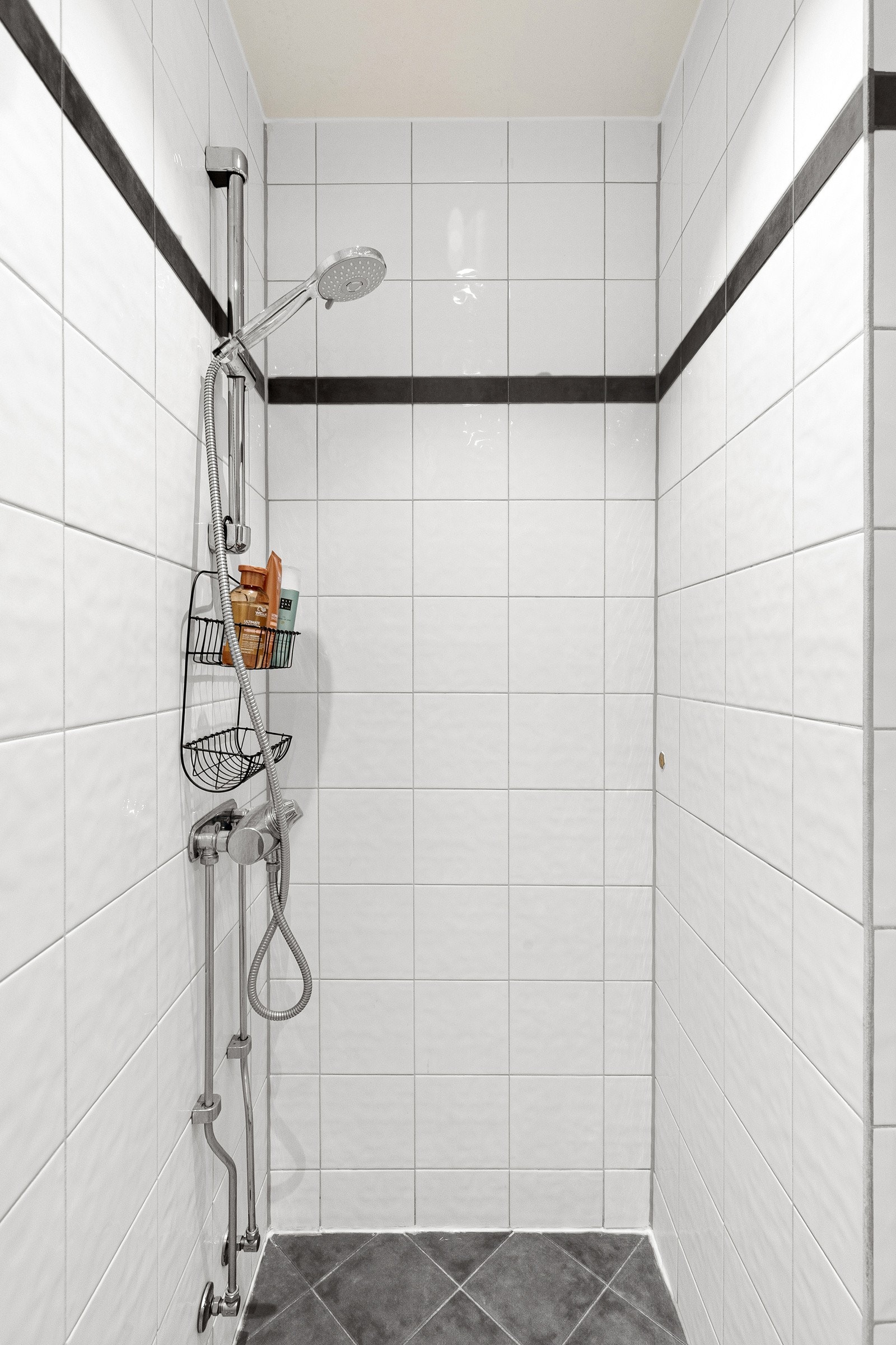 Ellers er badet utstyrt med gulvstående servantskap med ovenpåliggende servant, dusjsone med dusjforheng og gulvstående toalett. Galleribilde