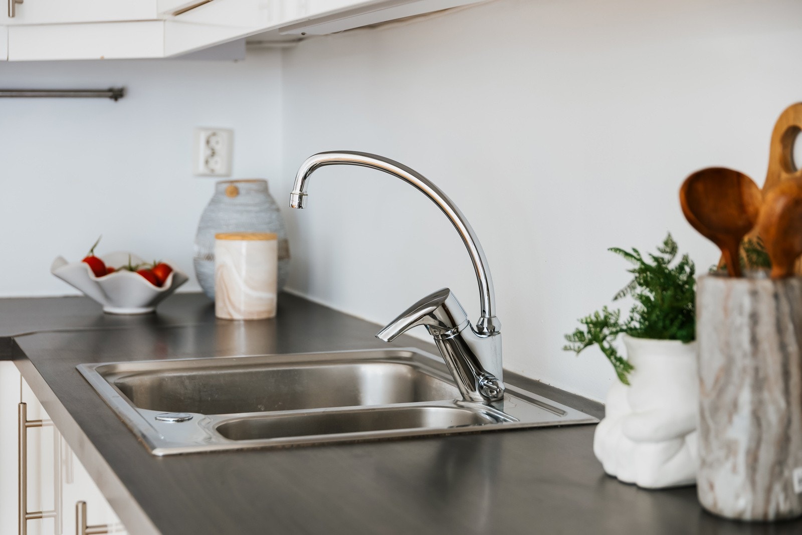 Innredningen på kjøkkenet består av glatte og moderne fronter, belysning under overskap, laminat benkeplate med nedfelt kum i rustfritt stål Galleribilde