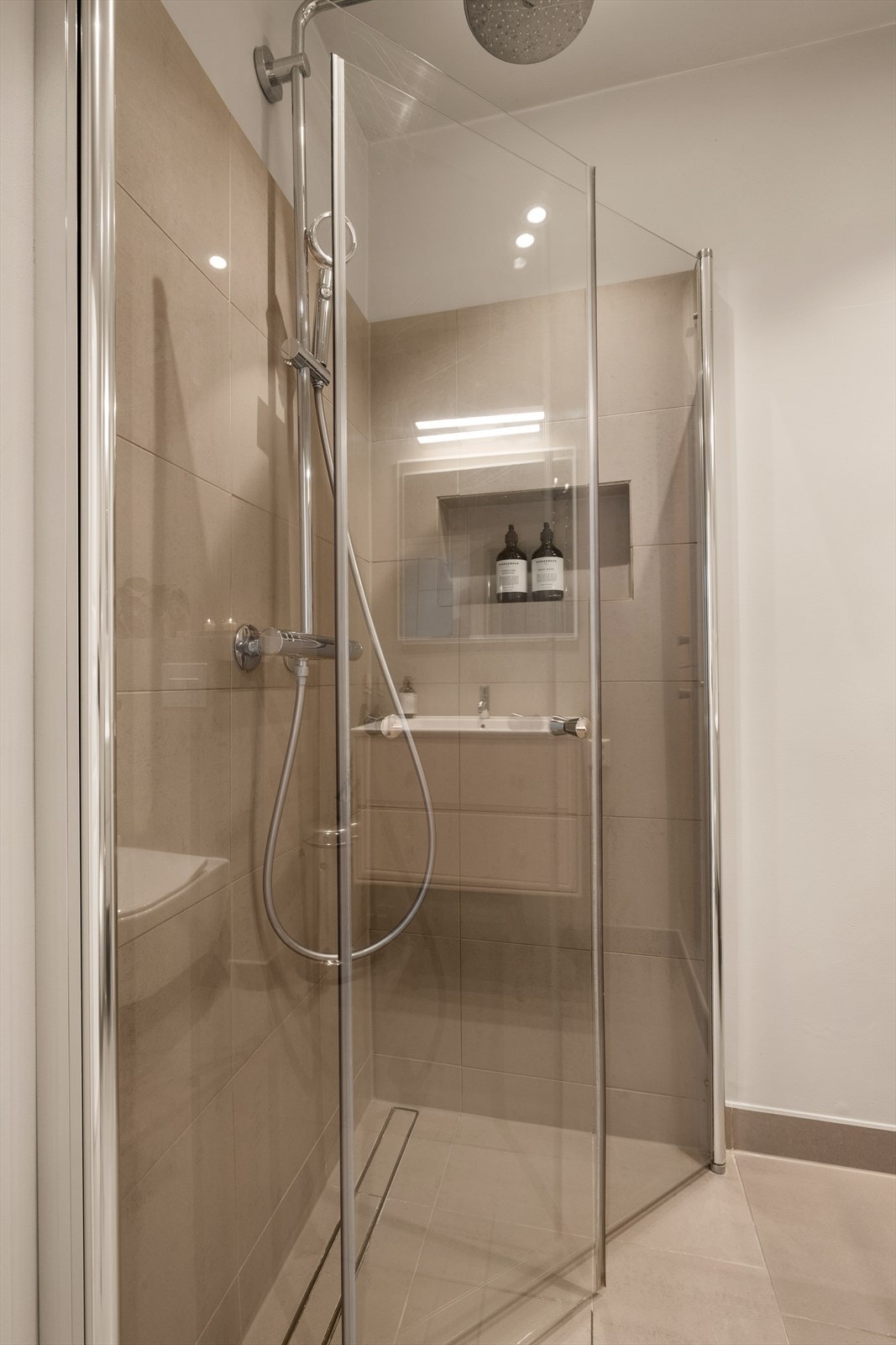 Dusjhjørne med innfellbare glassdører og dusjarmatur tilkoblet hånddusj og regnfallsdusj Galleribilde