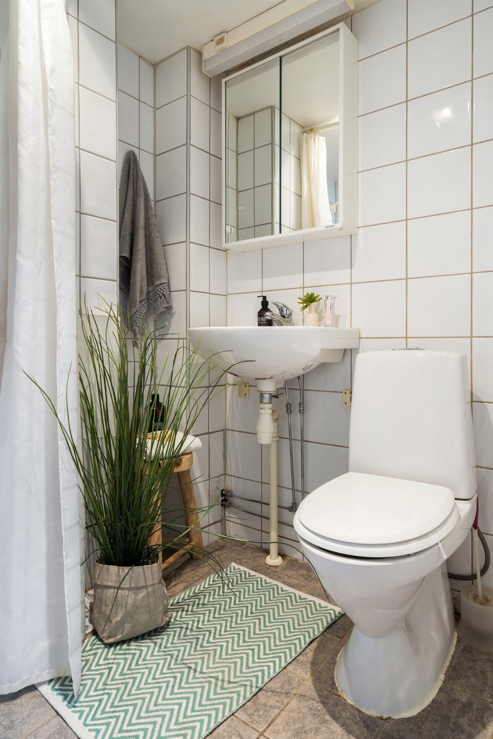 Rommet er innredet med vegghengt servant med ett-greps armatur, speilskap med overlys, dusjhjørne og gulvstående toalett. Galleribilde