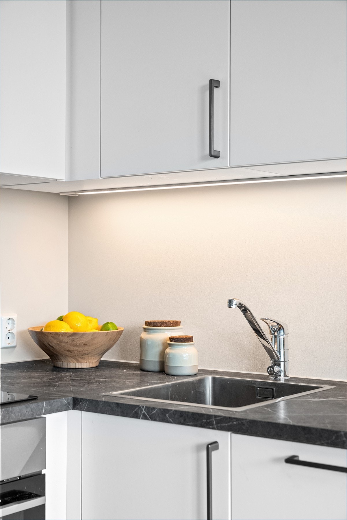 Oppgradert benkeplate med steinmønster og nedfelt kum i rustfritt stål samt lys under overskap Galleribilde