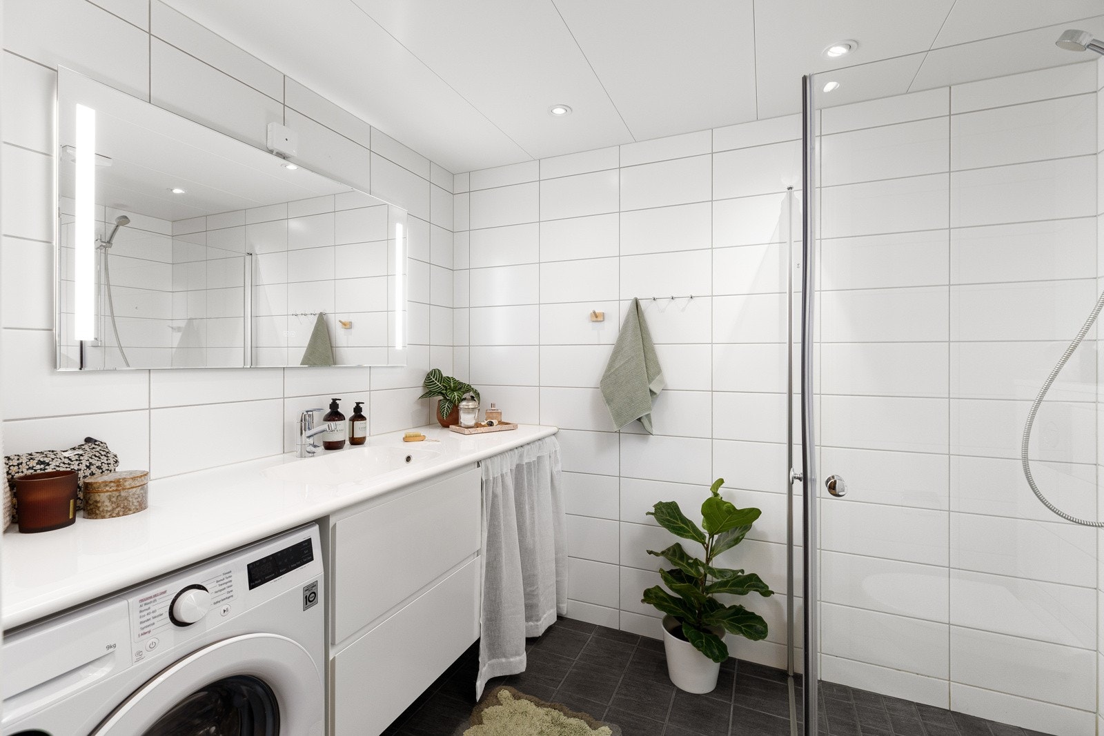 Badet har lekre, lyse fliser på veggene og mørke gulvfliser. Galleribilde