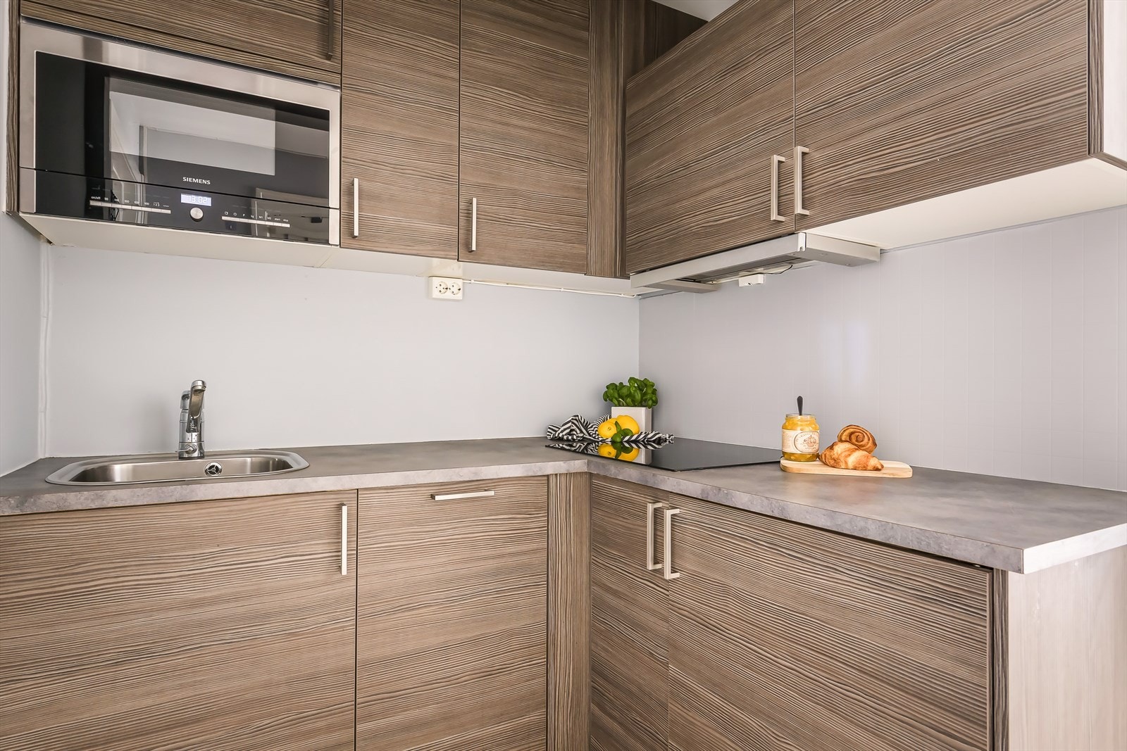 Sigdal kjøkkeninnredning fra 2012 med glatte fronter og integrerte hvitevarer bestående av stekeovn, platetopp, kjøleskap og oppvaskmaskin. Galleribilde