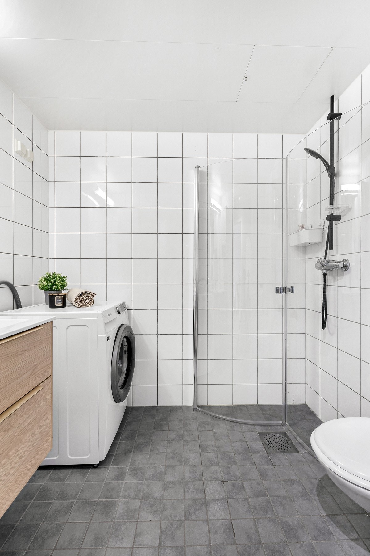 Badet er innredet med dusj hjørne med glassdører fra 2024, vegg hengt toalett, innredning med nedsunket servant fra 2024 med speil samt opplegg for vaskemaskin. Galleribilde