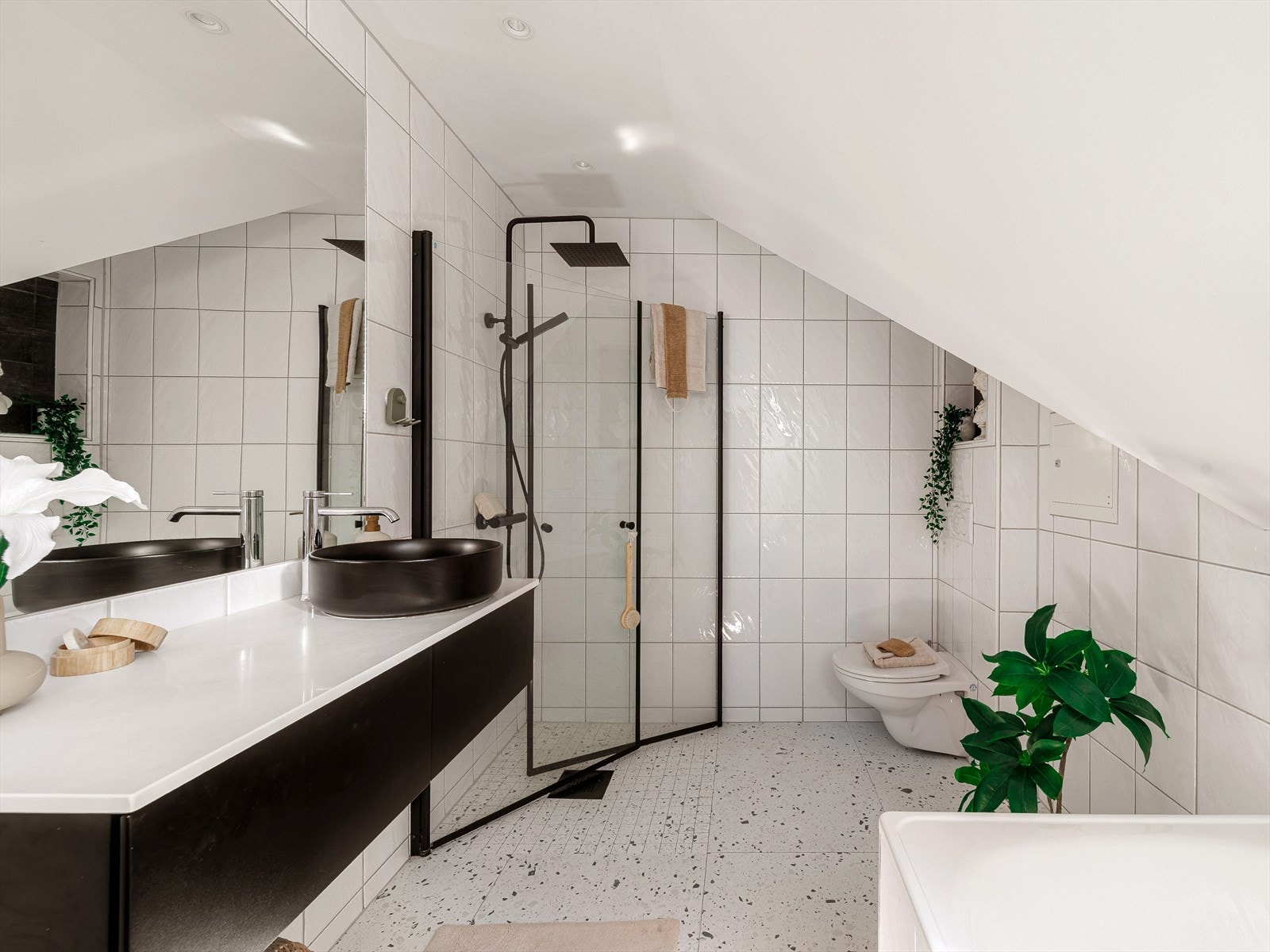 Flott helfliset bad med varmekabler i gulv. Badet er utstyrt med servant med underskap og speil, dusjhjørne, vegghengt toalett, opplegg for vaskemaskin og badekar. Galleribilde