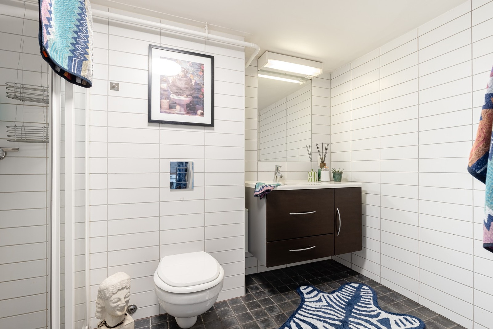 Pent, flislagt bad med gulvvarme. Badet er utstyrt med baderomsinnredning med servant, samt speil med lys over. Galleribilde