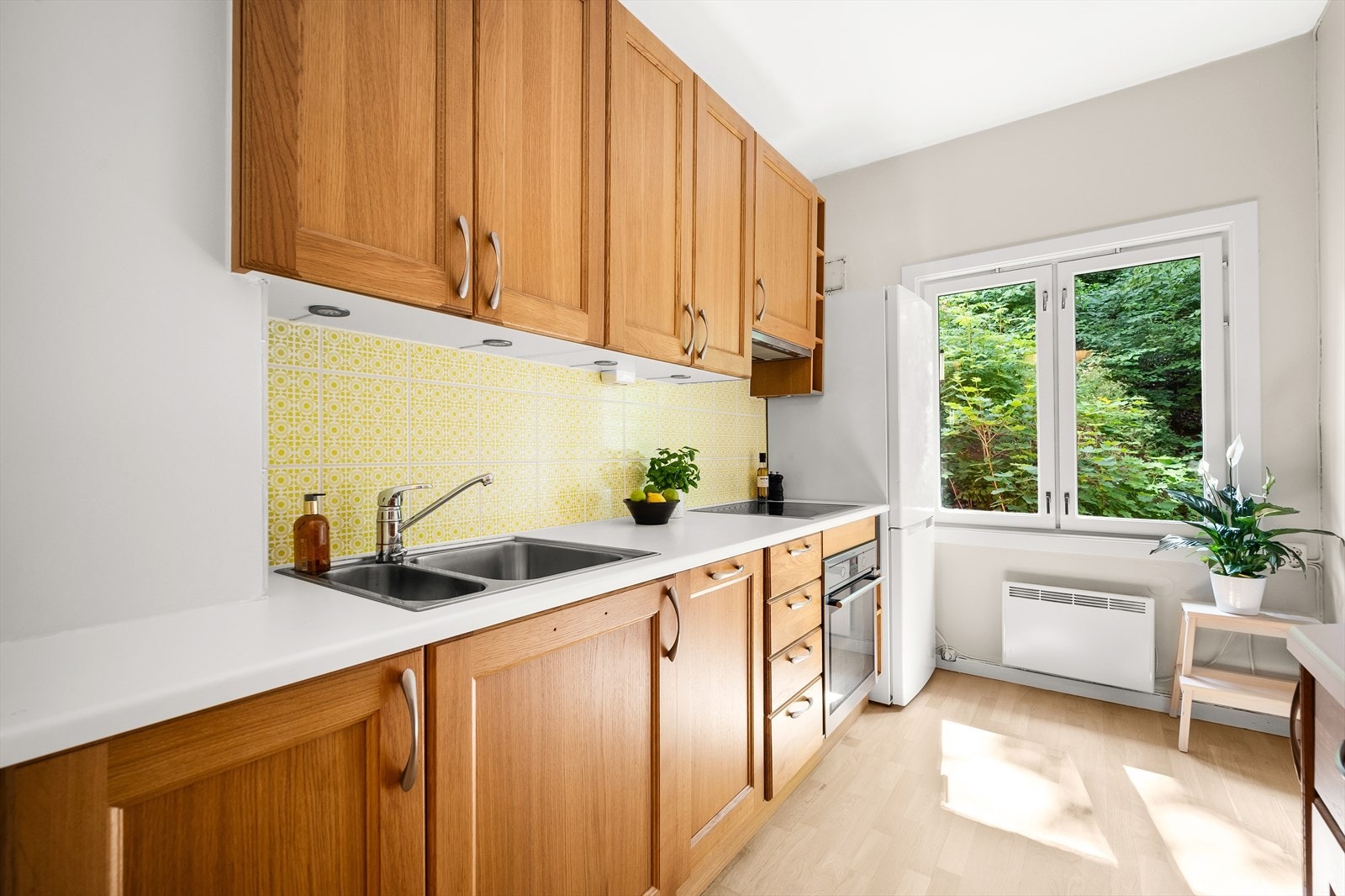 Kjøkkeninnredningen består av profilerte fronter, laminat benkeplate, nedfelt oppvaskkum med ettgreps armatur fra Oras, lys under overskap og kullfiltervifte over stekesonen. Galleribilde