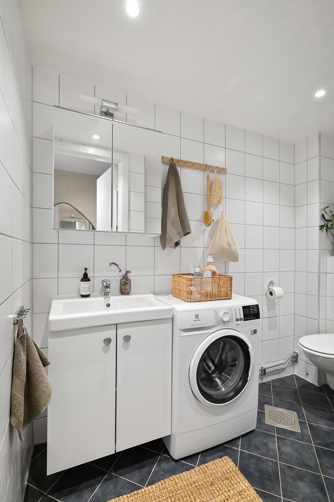 Et pent, flislagt bad med varmekabler, downlights i himling og opplegg for vaskemaskin Galleribilde