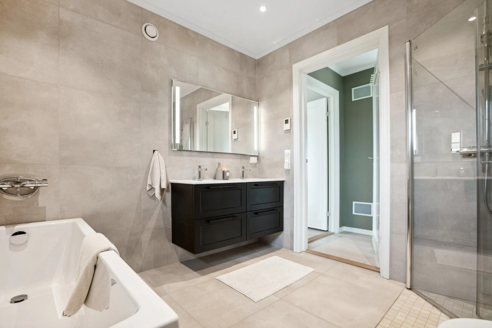 Baderommene har flislagte gulv og vegger i en lysere nyanse, som harmonerer godt med de mørke detaljene og skaper et stilfullt uttrykk. Galleribilde