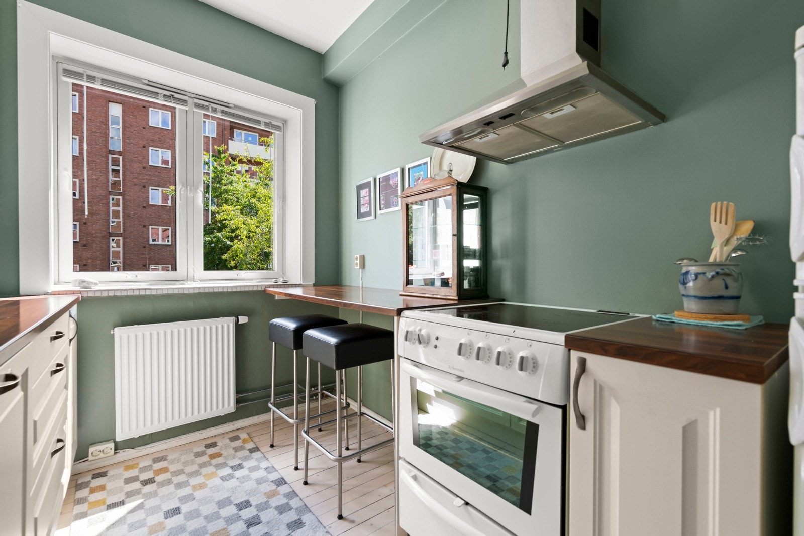 God benkeplass, to stilrene barkrakker og en klassisk komfyr - et hyggelig rom for både matlaging og små måltider. Galleribilde