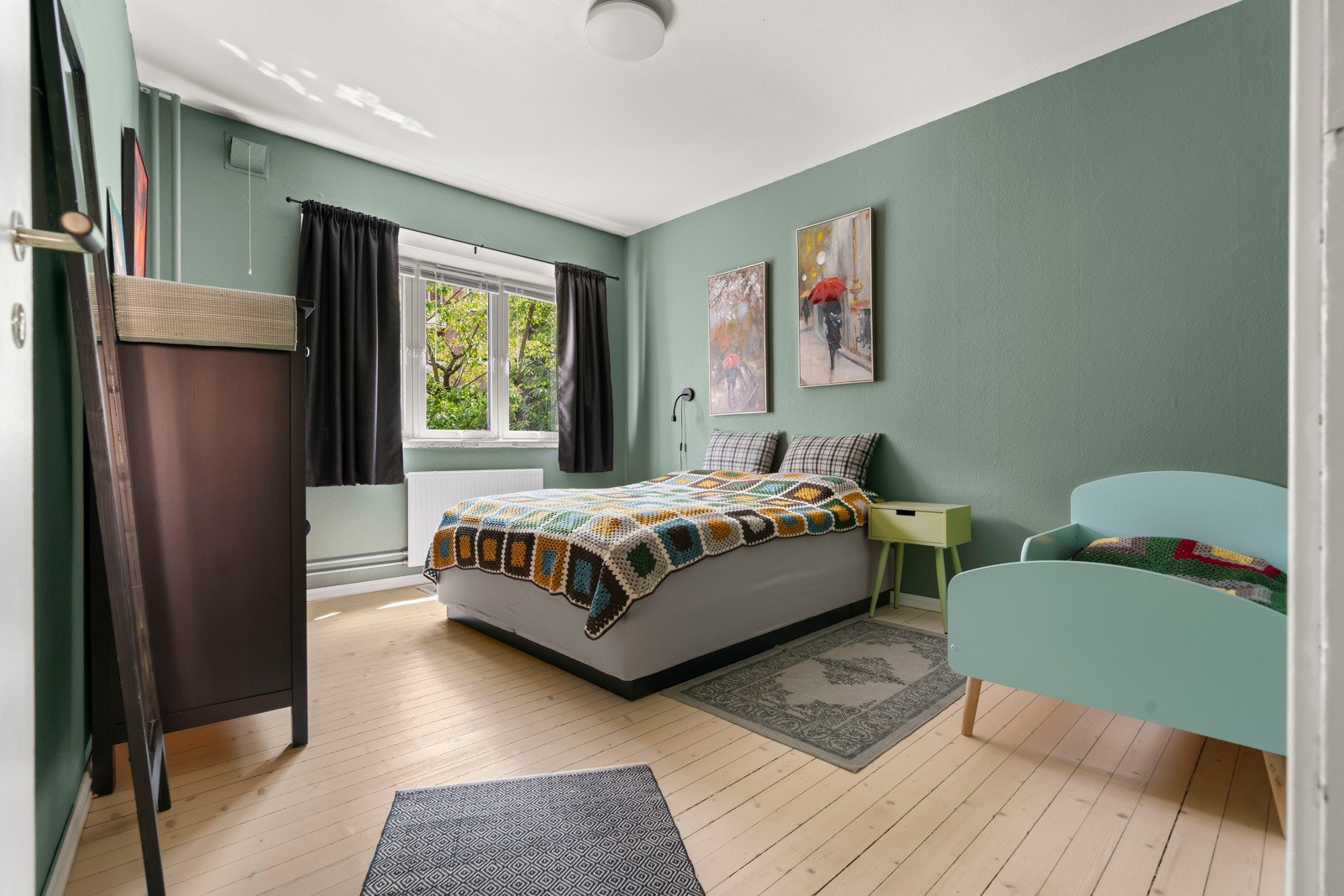 Stort soverom med delikate grønne vegger som er vendt ut mot frodig og skjermet bakgårdsmiljø. Galleribilde