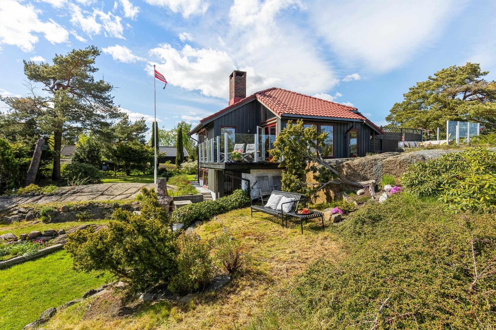 I den store, flotte hagen er det gressplen, prydbusker, fargerike blomsterbed, hekk og fjell i dagen. Galleribilde