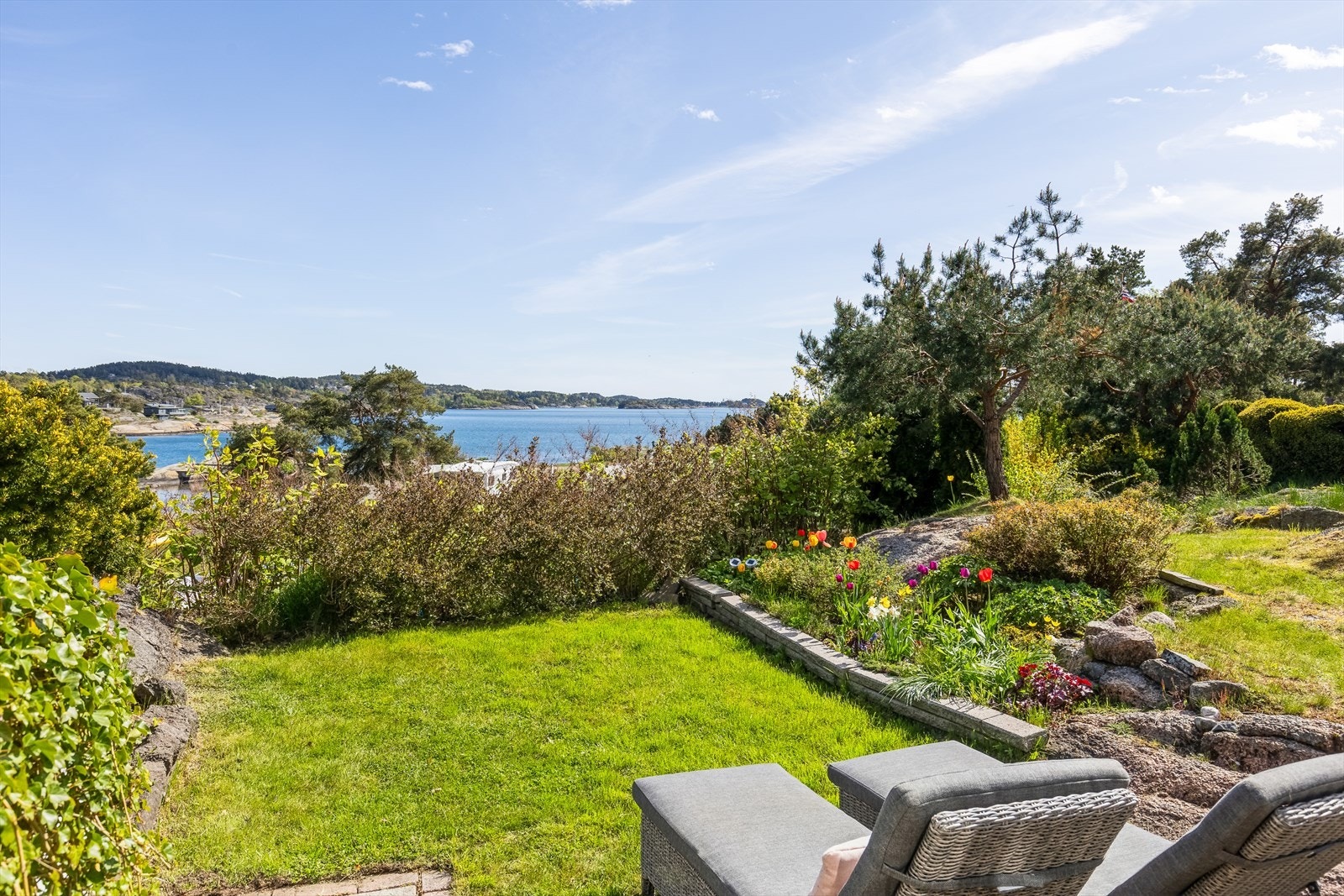 I den solrike hagen er det vakre blomsterbed og frodige prydbusker. Galleribilde