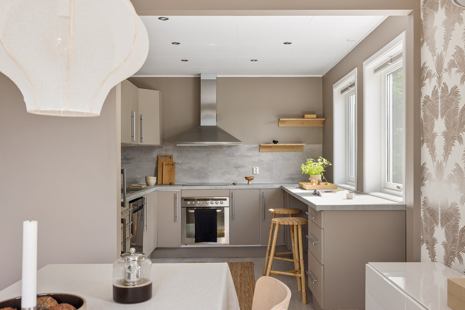 Flott kjøkken med beige malte og glatte fronter og laminat benkeplate. Galleribilde