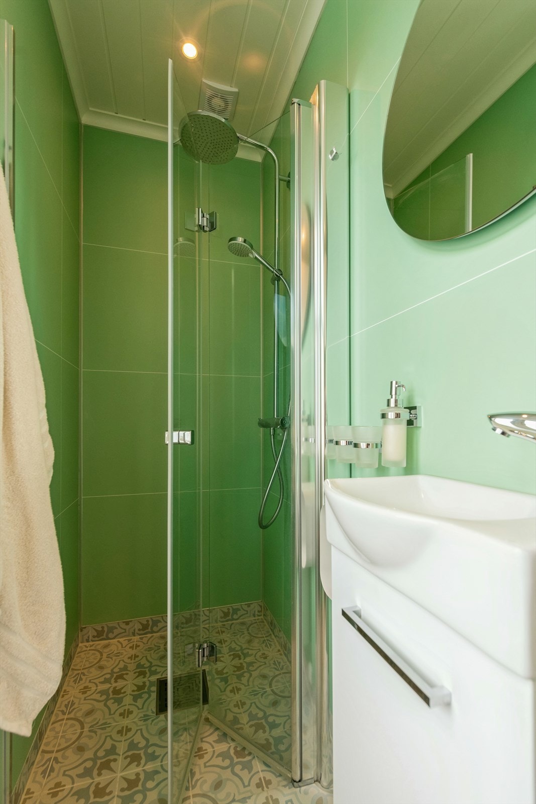 Badet er utstyrt med servant med underskap, speil og foldedør i glass til dusjsonen hvor det er elektrisk vifte i tak. Galleribilde