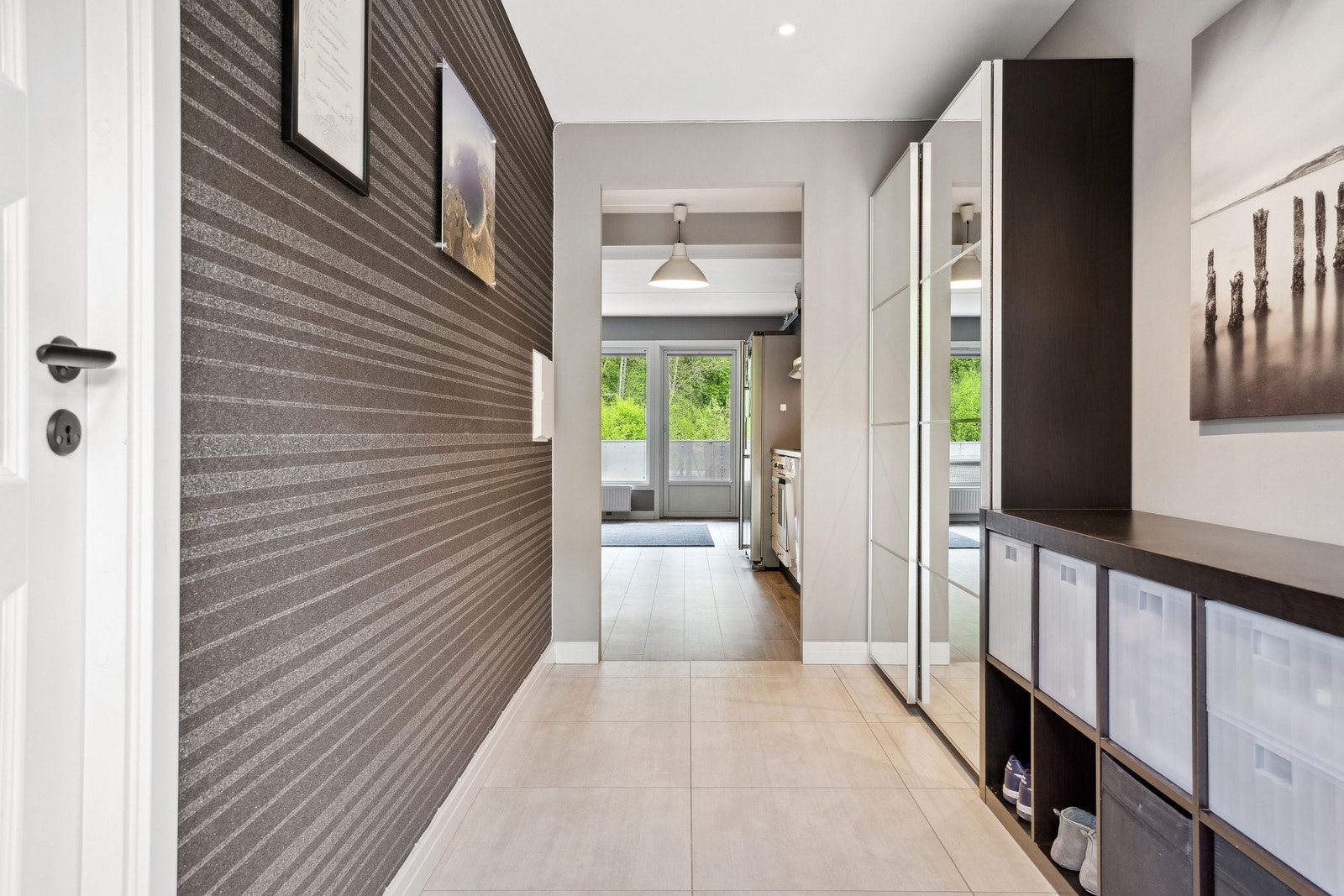 En romselig flisbelagt entrè med plass til garderobeskap og hyller. Garderobeskapet medfølger leiligheten. Entrè har både varmekabler i gulv og vannbåren varme. Galleribilde