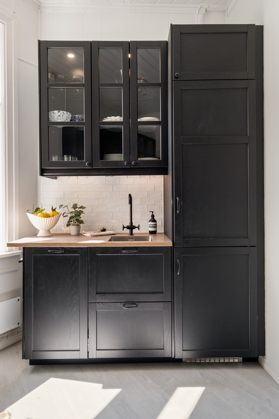 Profilert kjøkkeninnredning med malte fronter og laminert benkeplate med nedfelt koketopp og oppvaskkum av stål Galleribilde