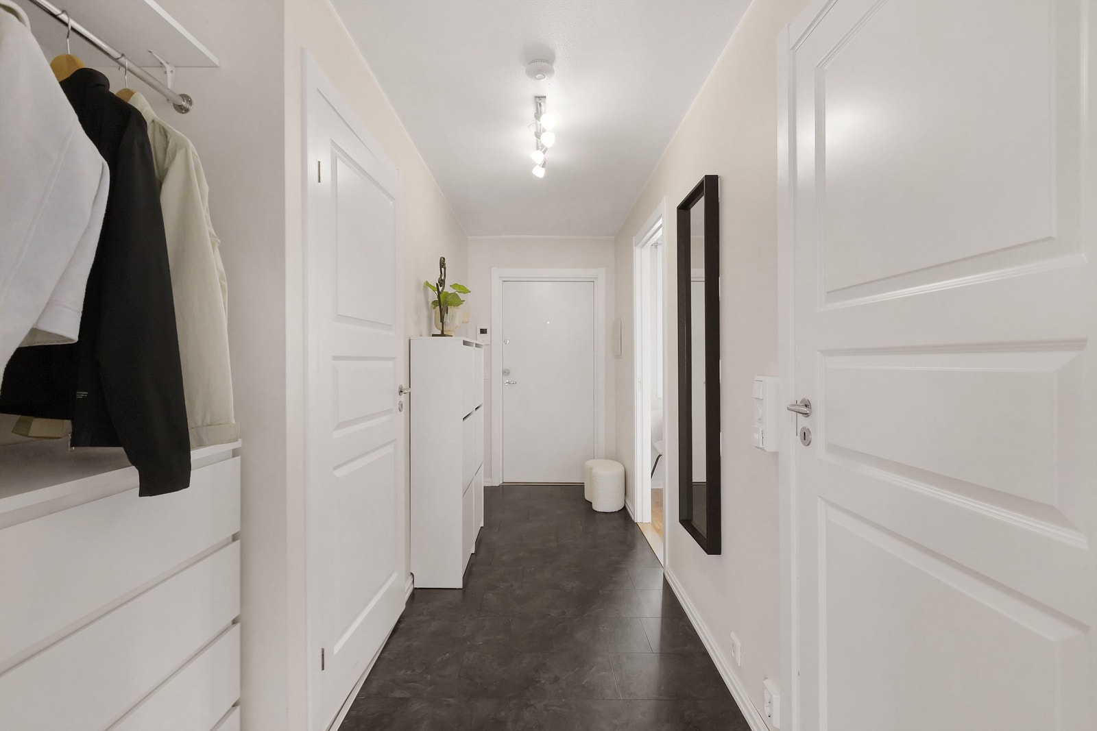 Innbydende entré med praktisk flislaminat på gulv. Her er det plass til oppbevaringsløsninger i tillegg til at det er god plass til klesoppheng i stor nisje. Galleribilde