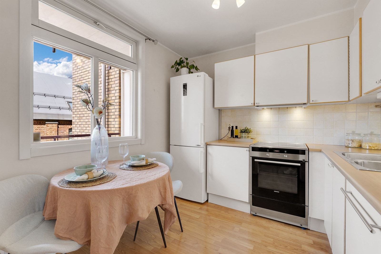 Pent kjøkken med innredning fra byggeår med hvite slette fronter. Hyggelig spiseplass ved vindu. Galleribilde