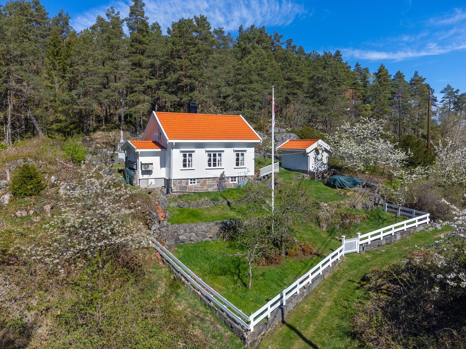 Det er pent opparbeidet med hvite gjerder og port som rammer inne eiendommen. Hagen består av plen på flere nivåer som inviterer til bruk og hygge. Galleribilde