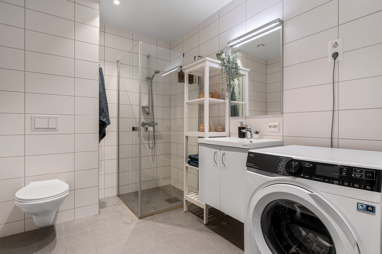 Flislagt, moderne bad med varmekabler og god plass for vaskemaskin.