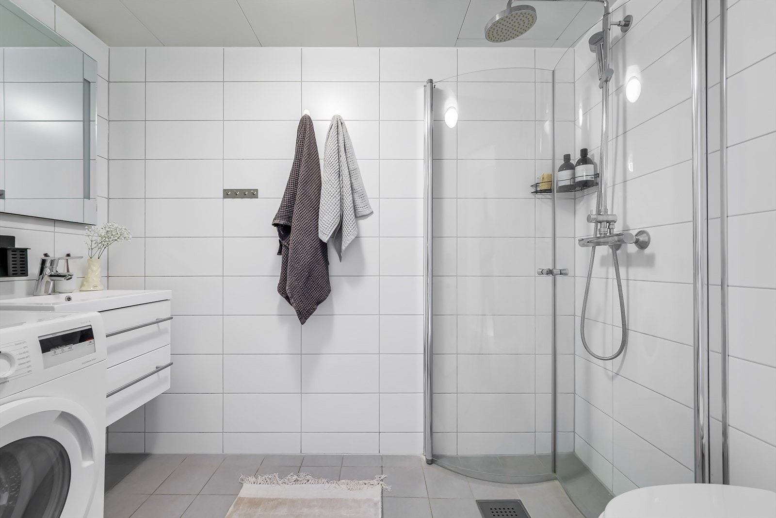 Innredning består av vegghengt servantinnredning med skuffer og ovenpåliggende servant, vegghengt speilskap med lys, dusjhjørne med glassdører og vegghengt dusjarmatur og vegghengt toalett. Galleribilde