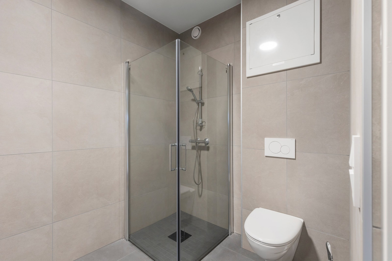 Videre er badet utstyrt med servantskap med speil og lys, vegghengt toalett og dusjhjørne. Galleribilde