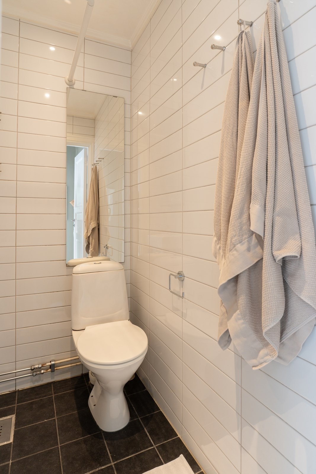 Mørkegrå og hvite fliser på henholdsvis gulv og vegger som gir rommet et tidløst uttrykk. Galleribilde