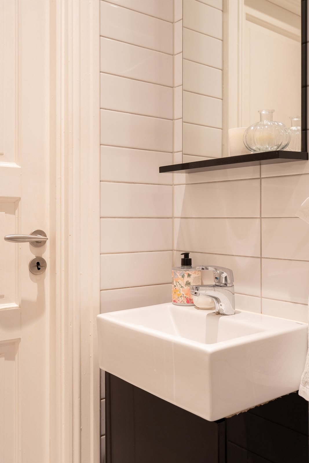 Baderom fra ukjent årstall med gulvvarme innredet med vegghengt servantskap med ett-greps armatur, vegghengt speil og toalett samt dushjørne. Galleribilde