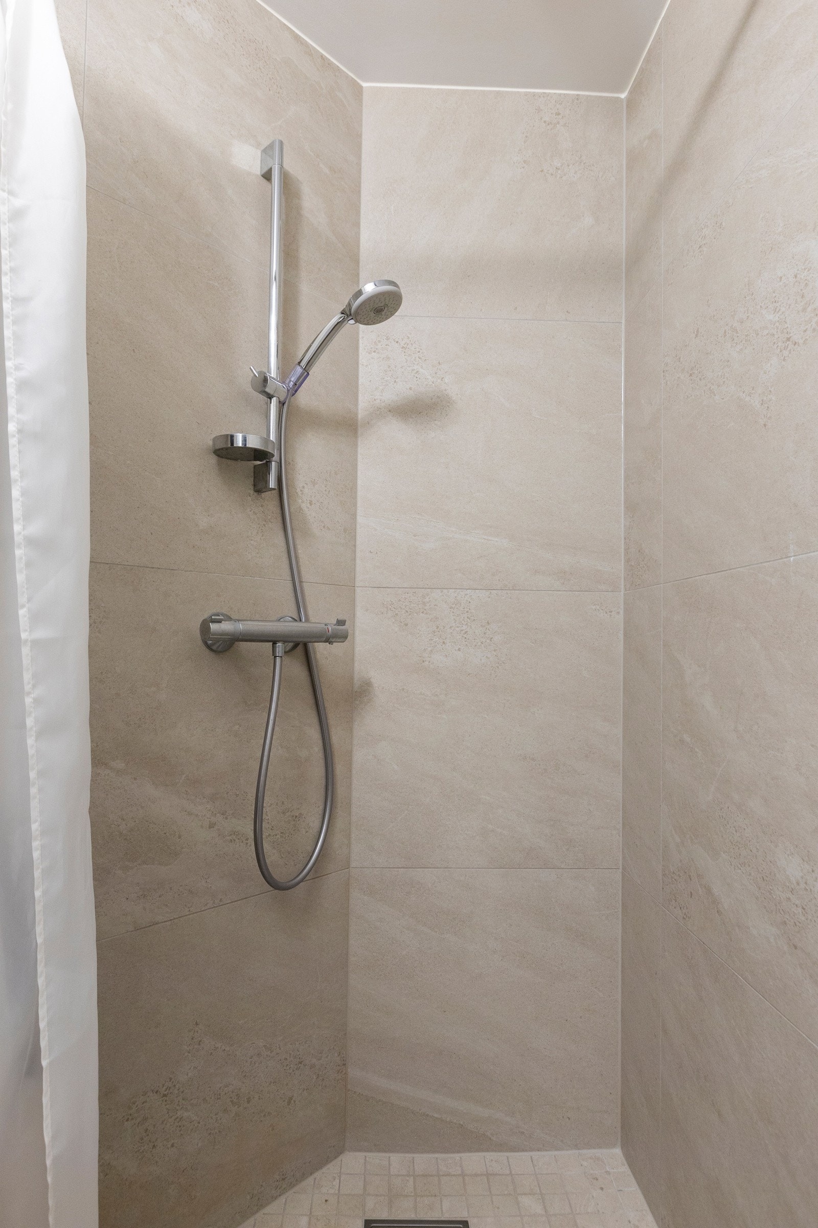 Dusjhjørne med nedsenket gulv og dusjforheng, samt termostatstyrt blandebatteri og dusjutstyr. Galleribilde