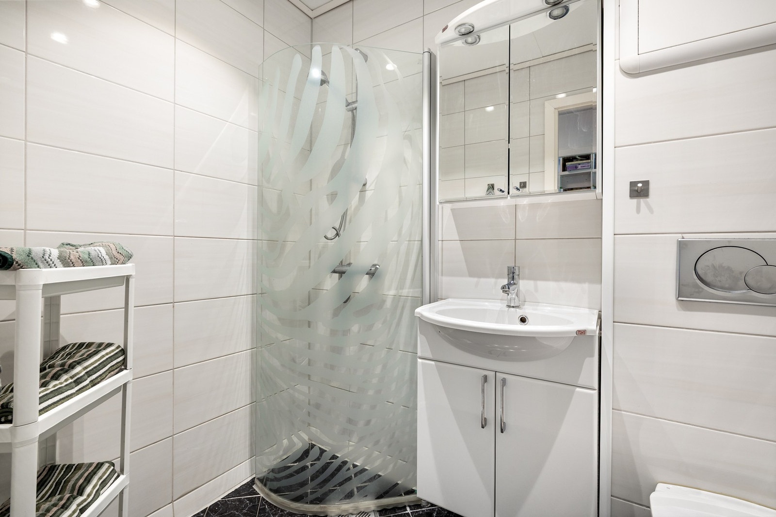 Fin bad med fliser på gulv og baderomsplater på vegg. Galleribilde