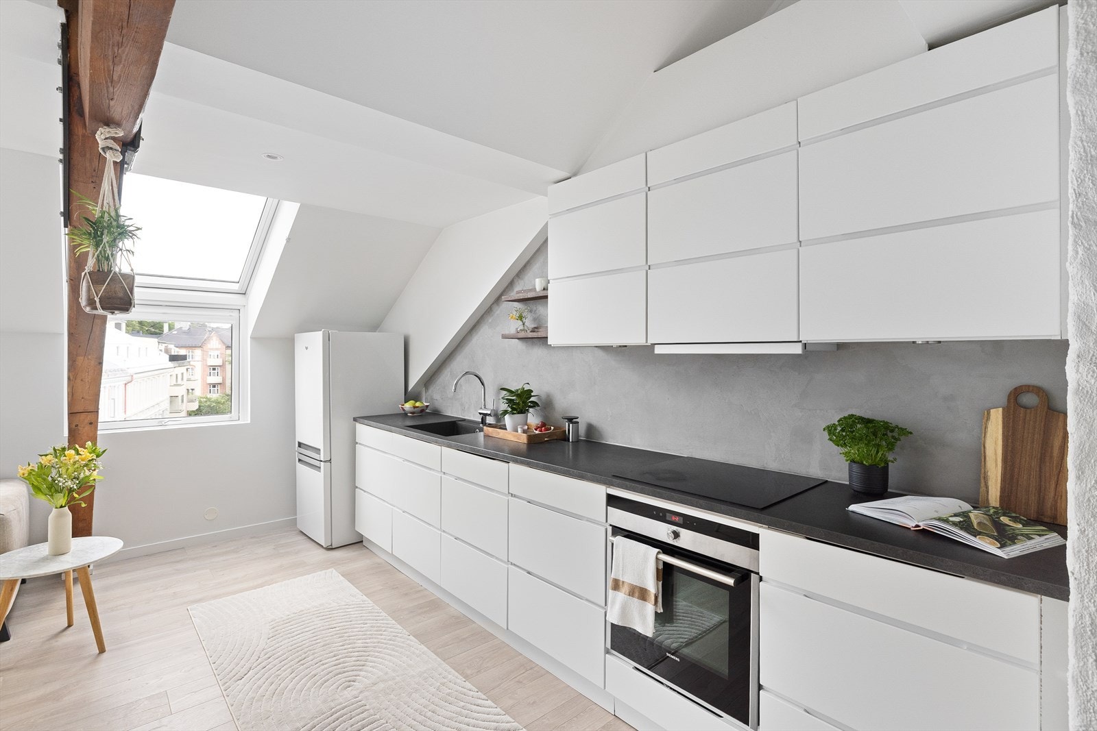 Lys innredning fra 2021 med glatte fronter og benkeplate i laminat. Malt mikrosement på vegg over kjøkkenbenken. Galleribilde