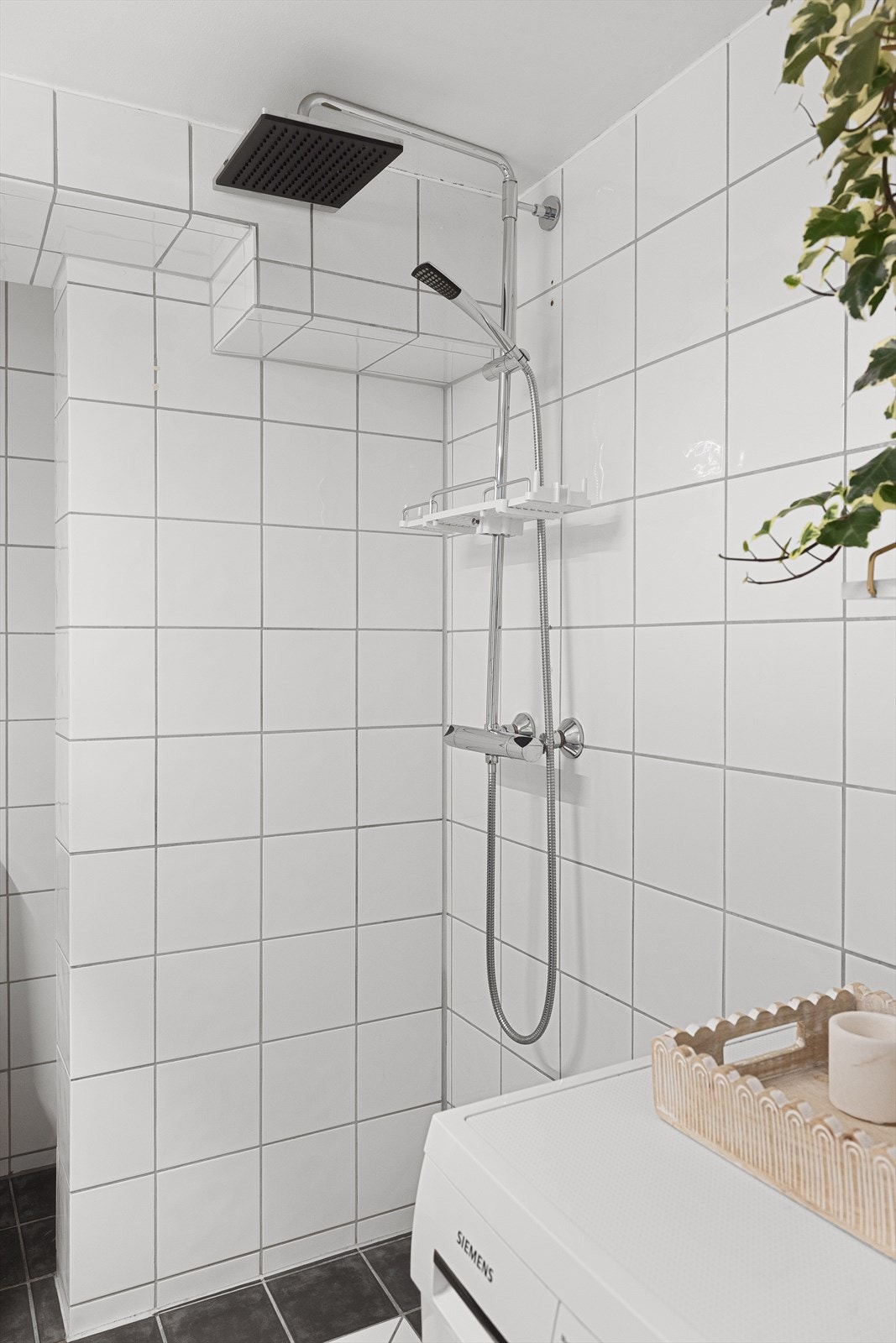 Badet inneholder dusj, gulvstående toalett og baderomsinnredning med skuffer, servant med ett-greps blandebatteri, speil på vegg og belysning. Galleribilde