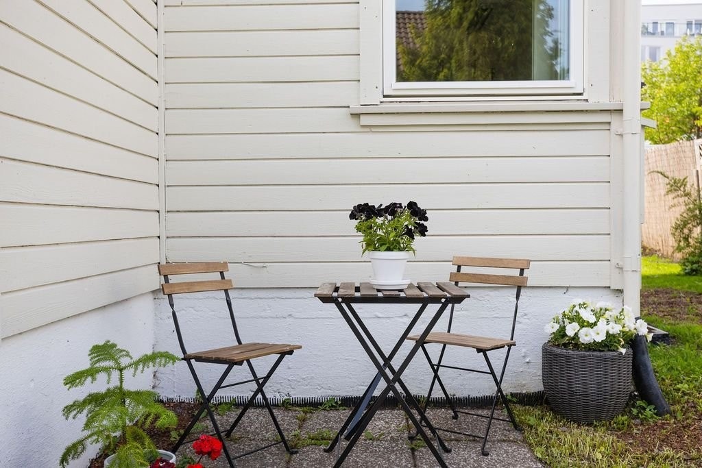 Forsiden av huset, med inngangspartiet og en lun krok med morgensol. Galleribilde