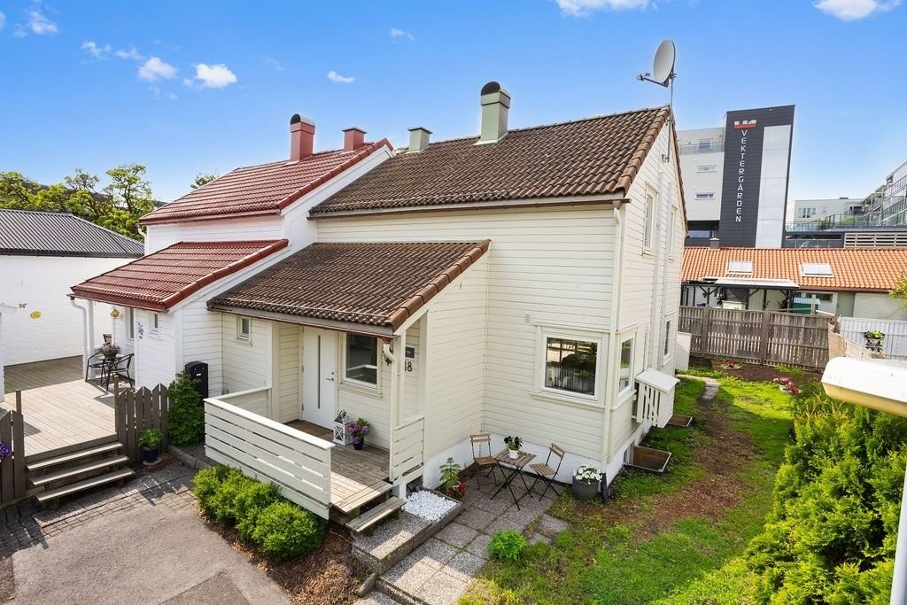 Forsiden av huset, med inngangspartiet og en lun krok med morgensol. Galleribilde