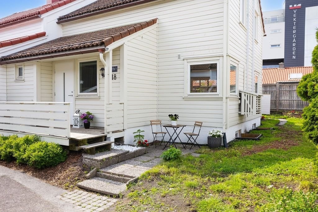 Forsiden av huset, med inngangspartiet og en lun krok med morgensol. Galleribilde