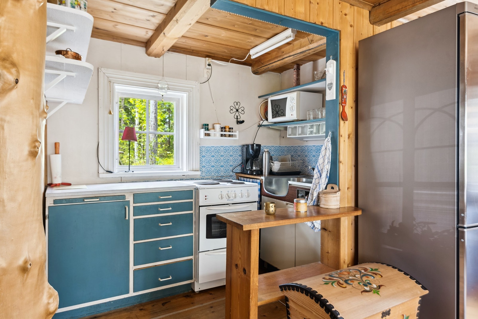 Kjøkkenet har eldre innredning, laminert benkeplate og nødvendige hvitevarer for enkel matlaging. Galleribilde